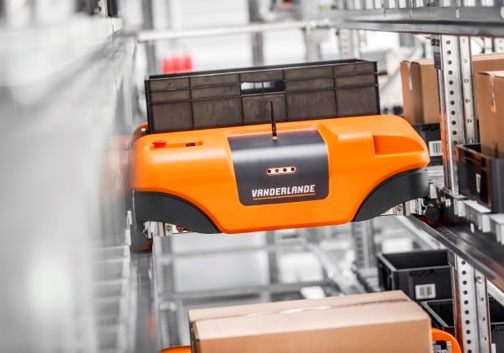 Photograph of the Vanderlande ADAPTO automated storage and retrieval shuttle system in a warehouse aisle.